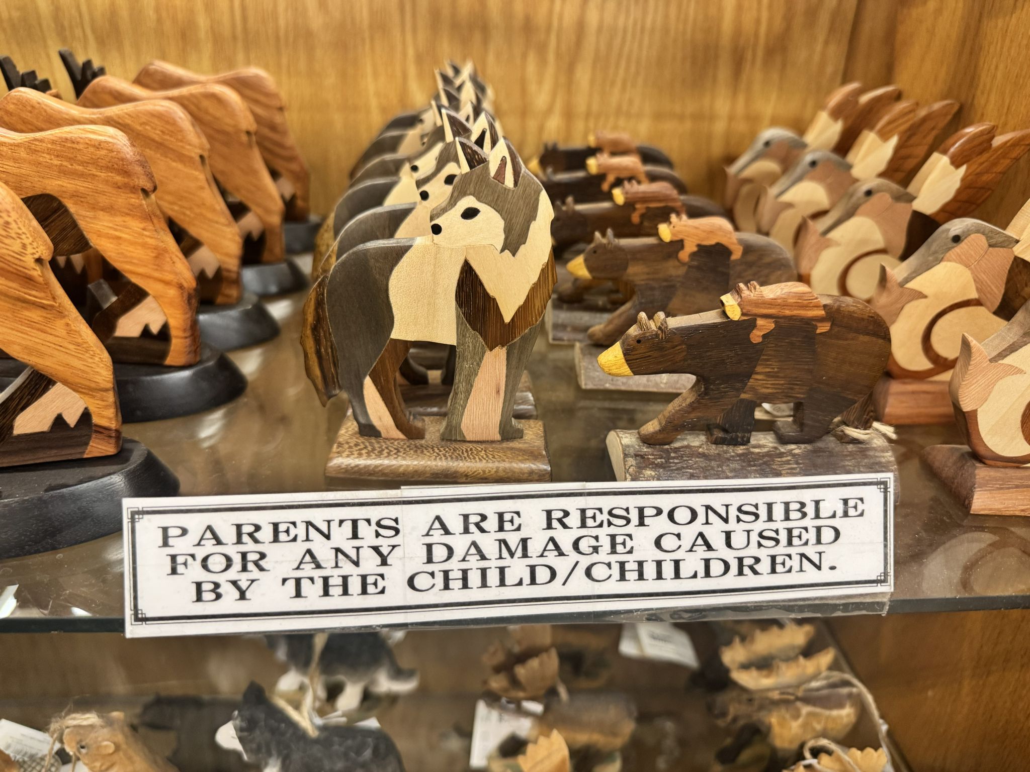 A small sign on a gift shop shelf reading: Parents are responsible for any damage caused by the child/children